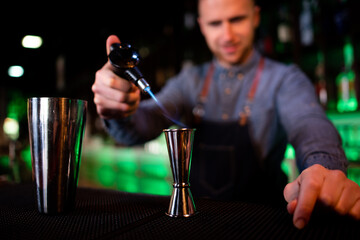 Young guy working as a bartender preparing cocktails in a pub