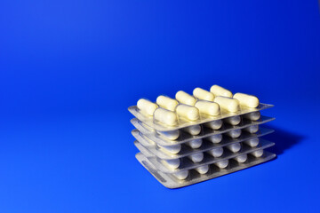 Pills in capsules in packpage on blue background. Medicine grade pharmaceutical tablets. Medical pill for maintaining and improving health. Antidepressant addiction and depression concept