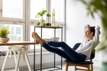 Young woman relaxing in office with her bare feet on desk 
