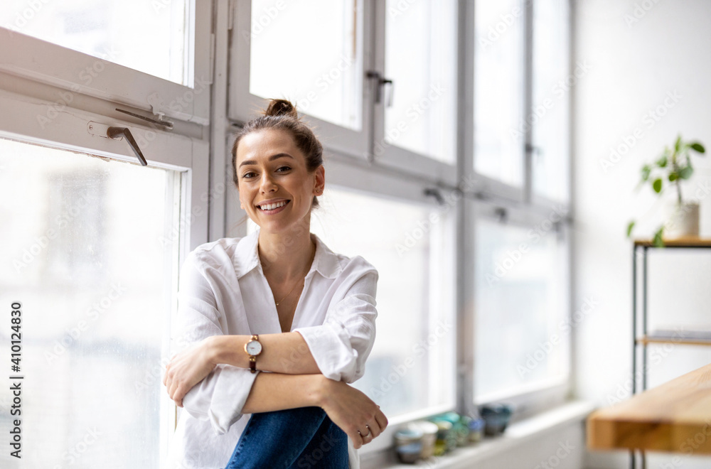 Wall mural Portrait of a smiling creative woman in a modern loft space
