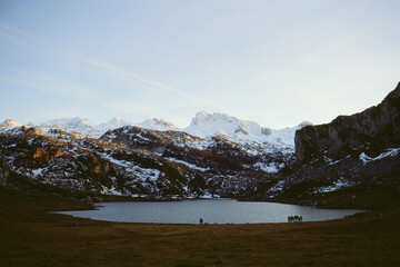 Lago en valle montañoso con picos nevados al atardecer