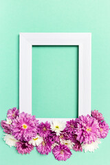 Empty photo frame and flowers on pastel green background