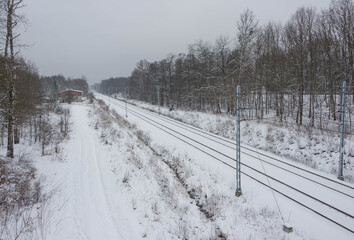 Dwutorowy szlak kolejowy zimą z przejeżdżającą lokomotywą elektryczną. © boguslavus