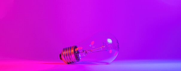 Photo of light bulb lamp in neon light. Ideea concept isolated on pink blue background, for electrician maintenance, craftsman, handyman