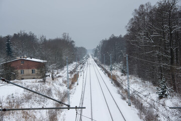 Dwutorowy szlak kolejowy zimą z przejeżdżającą lokomotywą elektryczną. - obrazy, fototapety, plakaty