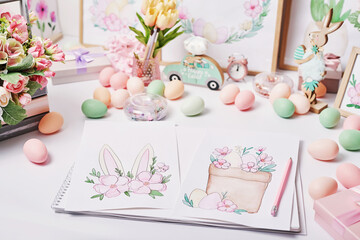 Easter eggs and flowers. Spring greeting card Happy Easter. Easter decor. Watercolor spring paintings. Designer and artist's workplace. Creative space