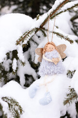 A soft textile doll with golden heart in hands sitting on the snow. Valentine’s Day, love, Merry Christmas, New Year concept.