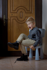Preschooler child learning to tying shoelace at home, selective focus. Vertical format