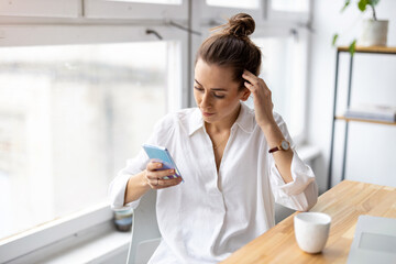 Creative business woman using smartphone in loft office
