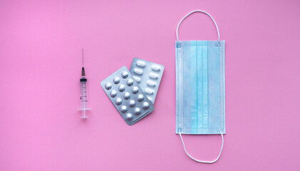 Fototapeta na wymiar Medical syringe, protective mask and pills on pink background, health and vaccination concept. Flat lay with space for text. 