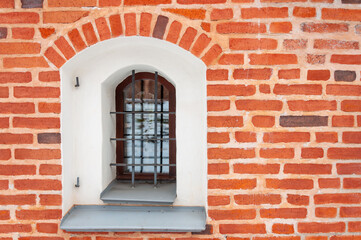 Window with lattice and gray sill. Part of an old building with red clay brick masonry
