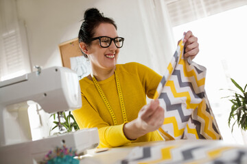 Woman sewing on a sewing machine at her home.