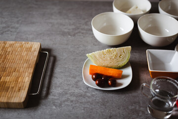 Fresh ingredients for vegetarian meal, on cooking table - carrot, cabbage and cherry tomato