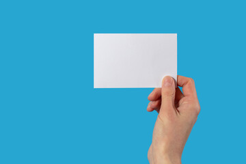 Human hand holds a blank sheet of paper on a blue background with blank space for text, concept for business or training