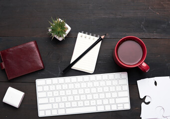 white wireless keyboard and wireless headphones and brown leather wallet on a wooden brown table