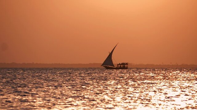 Fishermen's wooden dhow sailing at sunset in Zanzibar