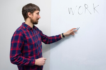 Young man writing on a white board in the office. Man makes a presentation. Trainings, education, startup. Business startup and entrepreneurship concept