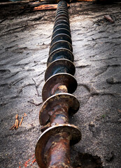 Auger for drilling in loose soil lies longitudinally on the paving stones