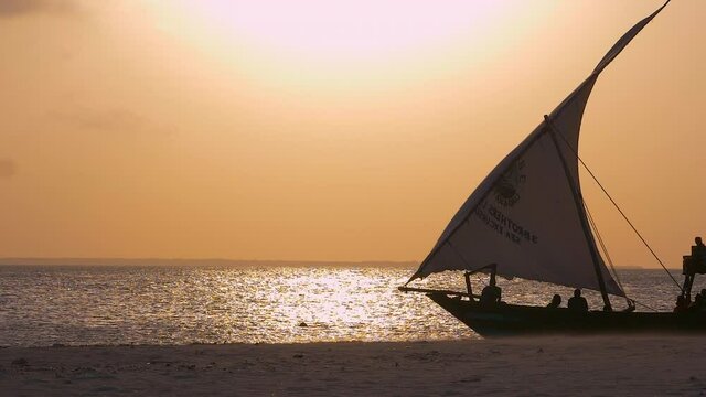 Fishermen's wooden dhow sailing at sunset in Zanzibar Tanzania