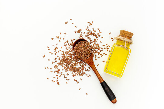 Flax seeds in a spoon and bowl with a bottle of flaxseed oil