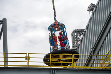 Offshore personnel being lifted with crane on a personal-transfer-basket from an oil production...