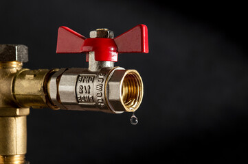 Ball valves close-up on a black background from which water is dripping. Plumbing renovation