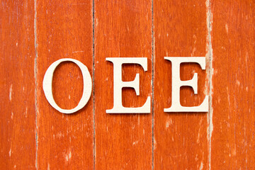 Alphabet letter in word OEE (abbreviation of overall equipment effectiveness) on old red color wood plate background