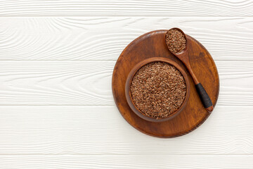 Flax seeds in a spoon and bowl with a bottle of flaxseed oil