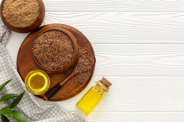 Flaxseeds in a spoon and bowl with a bottle of flaxseed oil and flaxseed flour