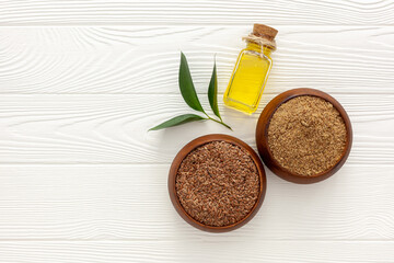 Flaxseeds in a spoon and bowl with a bottle of flaxseed oil and flaxseed flour