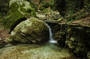 A small waterfall that flows over the boulders of a stream (Marche, Italy, Europe)