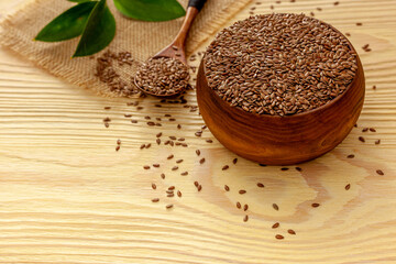 Flax seeds in a spoon and bowl with a bottle of flaxseed oil