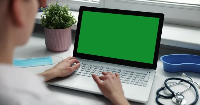 doctor working on laptop in clinic office. computer with green screen mockup