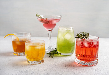 Five colorful summer cocktails in glasses on  white table. Assortment of fresh  summer drinks. Pink and red sangria cocktails, orange punch cocktail, margarita cocktail, tropical mule.