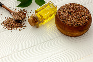 Flax seeds in a spoon and bowl with a bottle of flaxseed oil