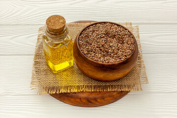 Flax seeds in a spoon and bowl with a bottle of flaxseed oil