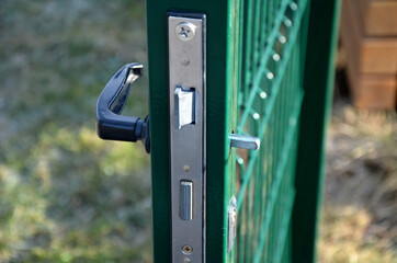 torn door handle on a metal green gate to the garden. Danger of closing and not getting out. vandalism of young 