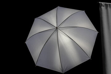 White silver reflective photo umbrella on a black background as an illustration or art design...