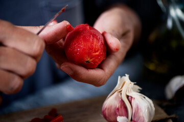 young man peeling a scalded tomato