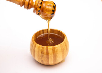 Natural tastey honey pouring with dipper into wooden bowl