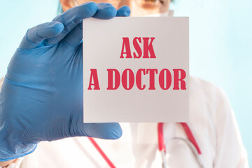 Female doctor in blue latex gloves holding a tablet with the text: ASK A DOCTOR