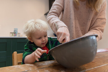 Mother and child mixing ingredients in a bowl in the kitchen together.