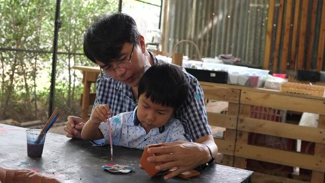 4K Authentic asian cute child boy painting with father. Son and dad have happy family activity together in holidays. Concept of father's day, fatherhood, art, little artist.