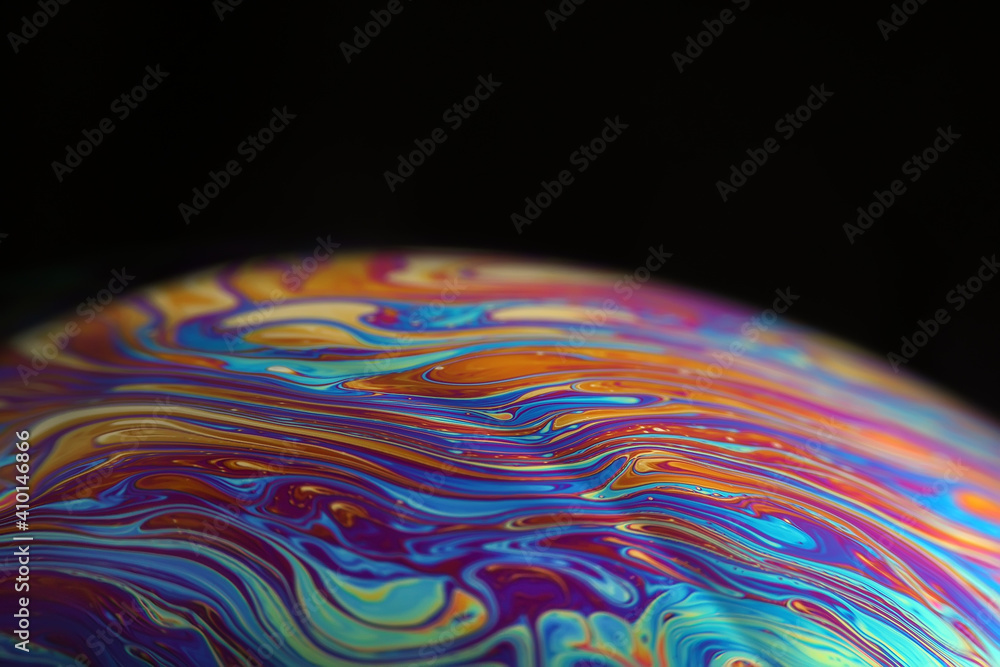 Wall mural macro picture of half soap bubble on black ground look like abstract psychedelic color planet in spa