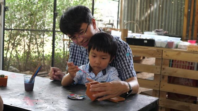4K Authentic asian cute child boy painting with father. Son and dad have happy family activity together in holidays. Concept of father's day, fatherhood, art, little artist.