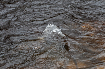 The ice floe in the river water is slowly melting.