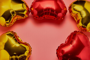 Air Balloons of heart shaped foil, red and gold, on a pink background. The concept of love, Valentine's Day, celebration, holiday. Metallic balloon. Flat lay. A place to copy.