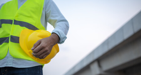 construction worker holding safety helmet at  construction site,