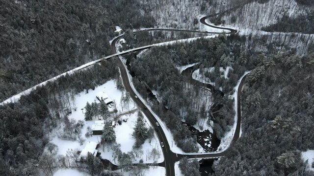 Beautiful winter scene of the road following small river through the woods covered in snow. Aerial revealing shot