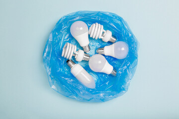 energy saving light bulbs in disposable plastic garbage bag on blue background for recycling. LED...